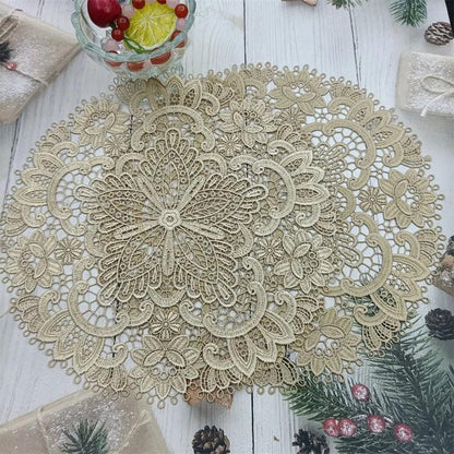 A detailed and intricately woven Costa Rica Coffee Friends &quot;European Classical Crochet Embroidery Exquisite Table Mat&quot; in beige lies on a white wooden surface, resembling classical European crochet embroidery. It features beautiful floral and geometric patterns. The table is adorned with festive elements including pine cones, holly, wrapped gifts, and a bowl filled with red cherries and lemon slices.