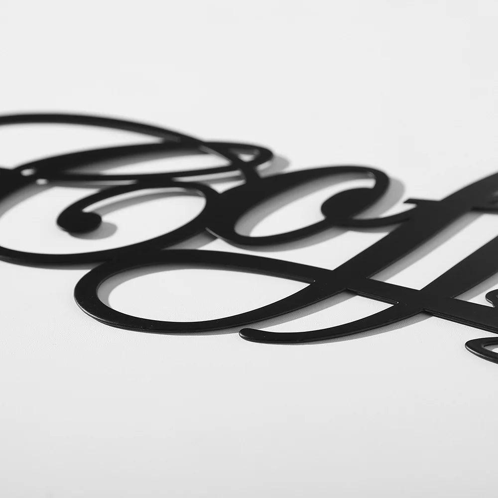 Close-up image of an intricately designed black script word &quot;COFFEE&quot; on a white background. The letters are connected and feature elegant, flourished lines, making this COFFEE Metal Word Cafe Wall Sign by Costa Rica Coffee Friends perfect for home decoration or metal wall art enthusiasts.